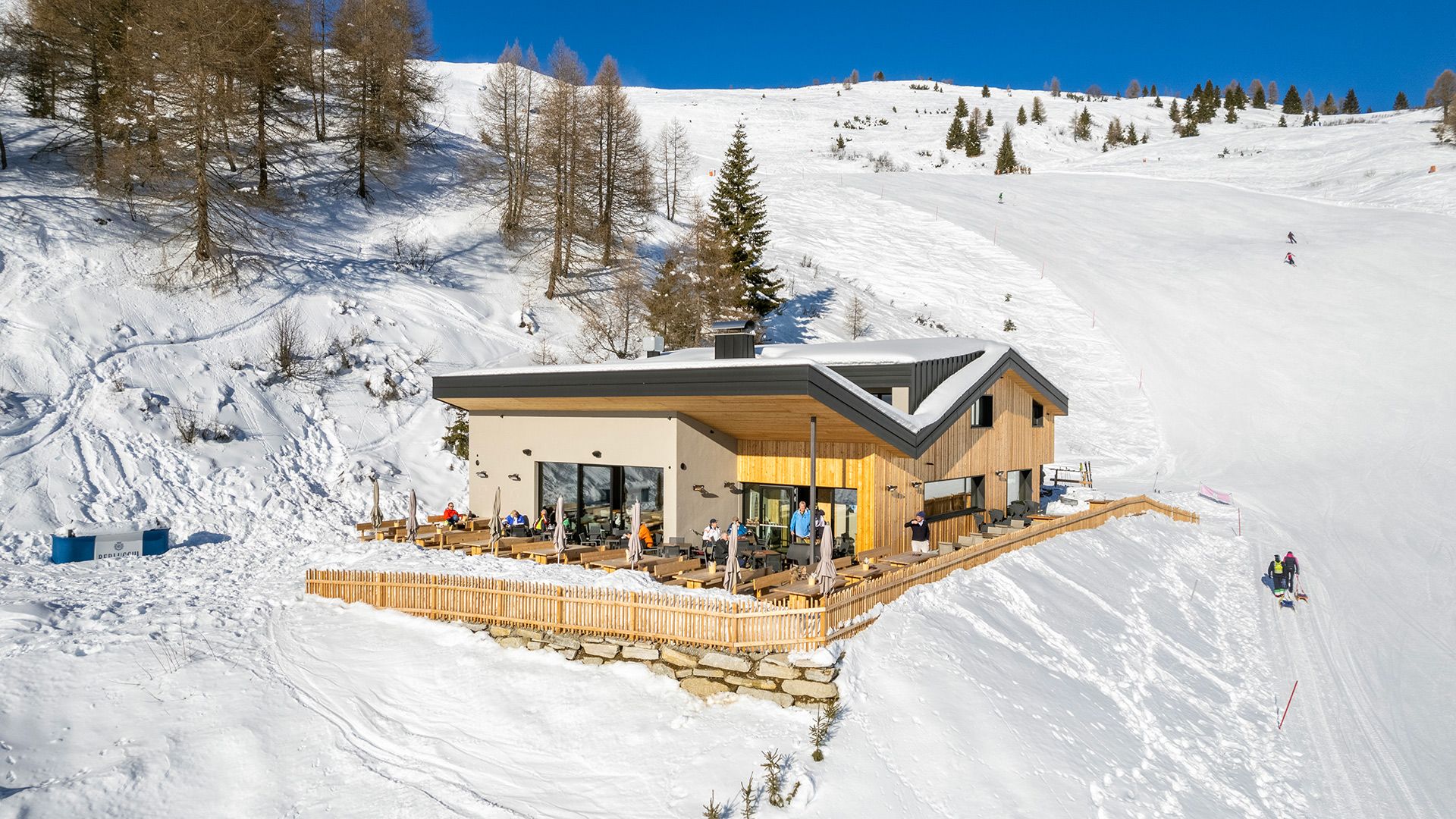 Alpin Chalet Rosskopf mit Gästen auf der Panoramaterrasse entlang der Skipiste des Monte Cavallo in Vipiteno im Winter